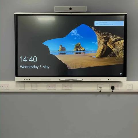 Interactive display with a video conferencing camera mounted above it in a meeting room