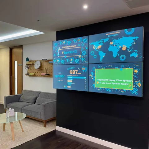 Four-screen videowall in a reception lounge displaying a world map and live statistics