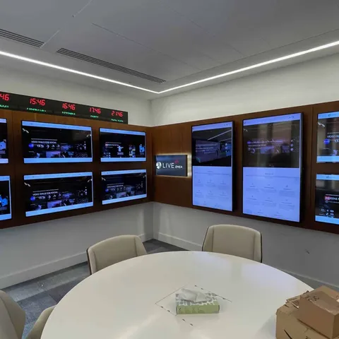 Meeting room surrounded by wall-mounted signage screens and a live ticker