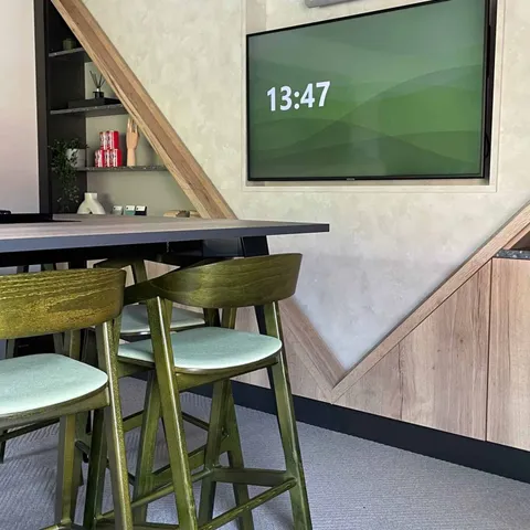 Wall-mounted display in a breakout area with bar stools and timber detailing
