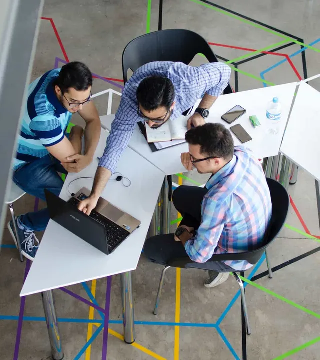 Three colleagues working together around a laptop during a training session
